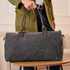 Gray duffel bag with black straps 