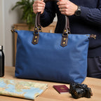 Blue duffel bag with black straps on a light gray background