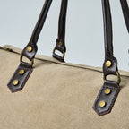 Beige duffel bag with black straps on a light gray background
