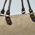 Beige duffel bag with black straps on a light gray background