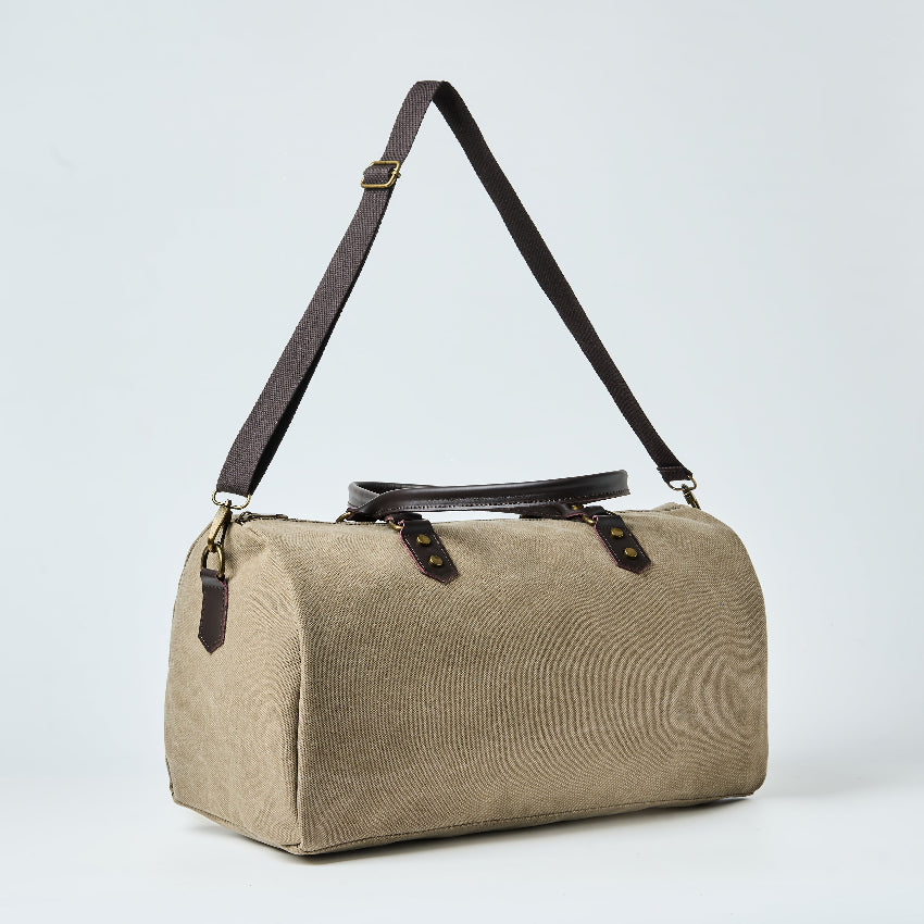 Beige duffel bag with black straps on a light gray background