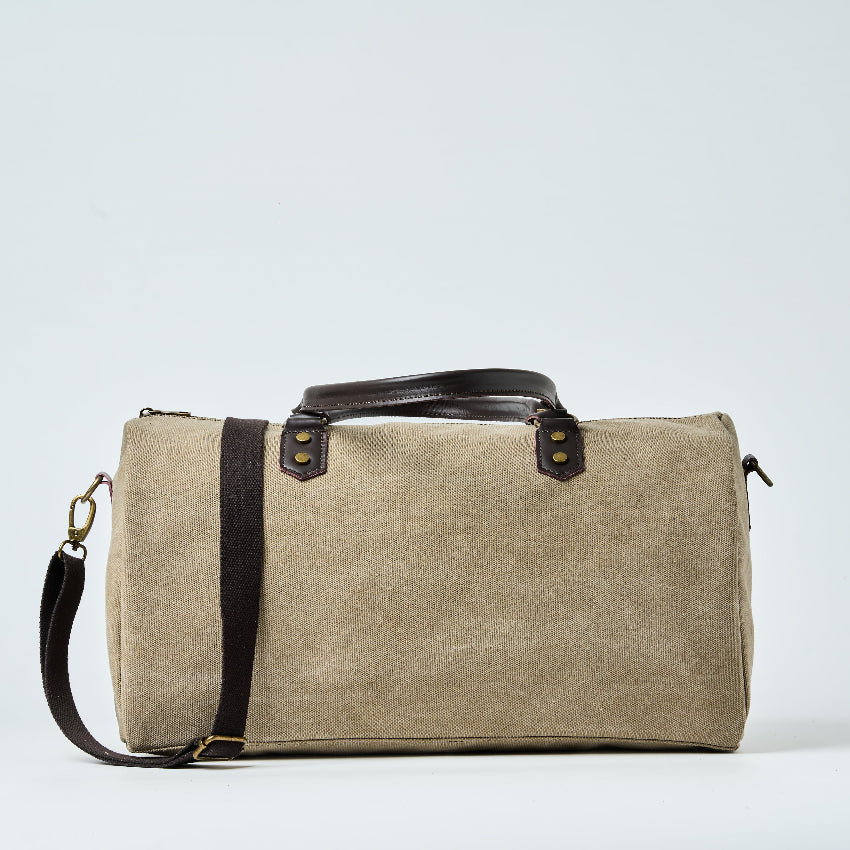 Beige duffel bag with black straps on a light gray background