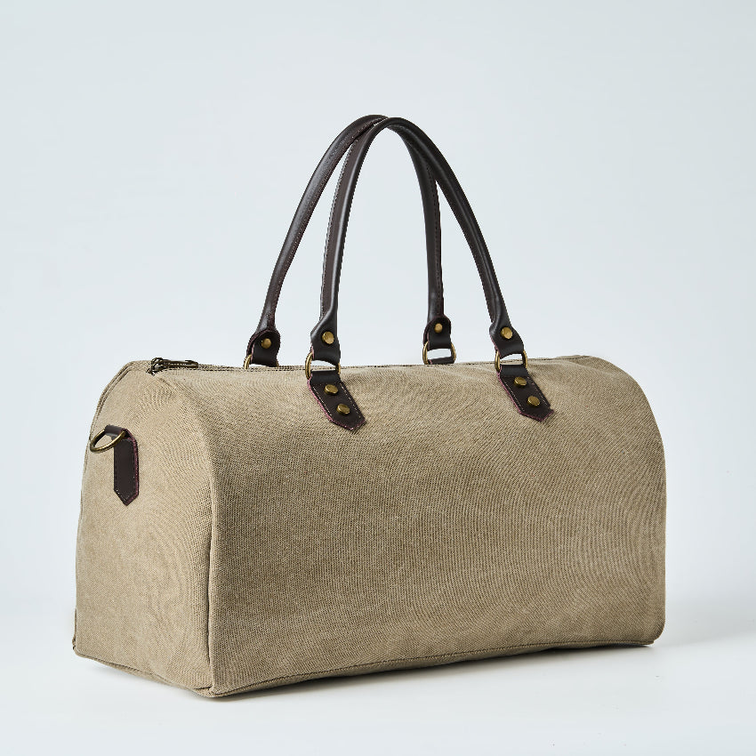 Beige duffel bag with black straps on a light gray background