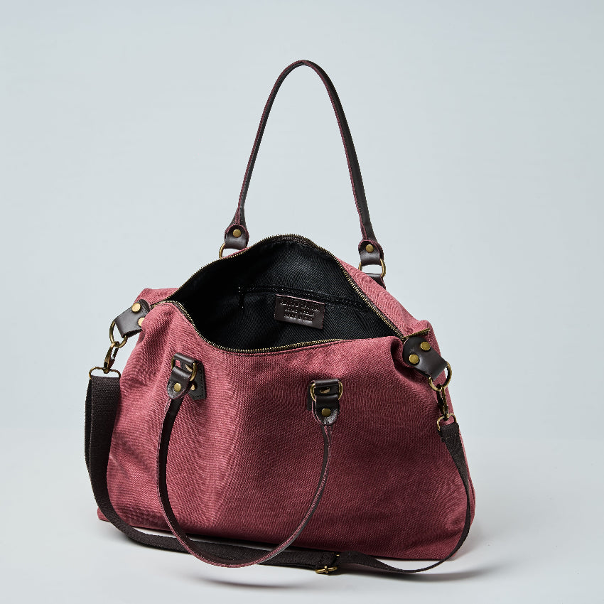 Burgundy tote bag with black straps on a light gray background
