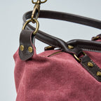 Burgundy tote bag with black straps on a light gray background