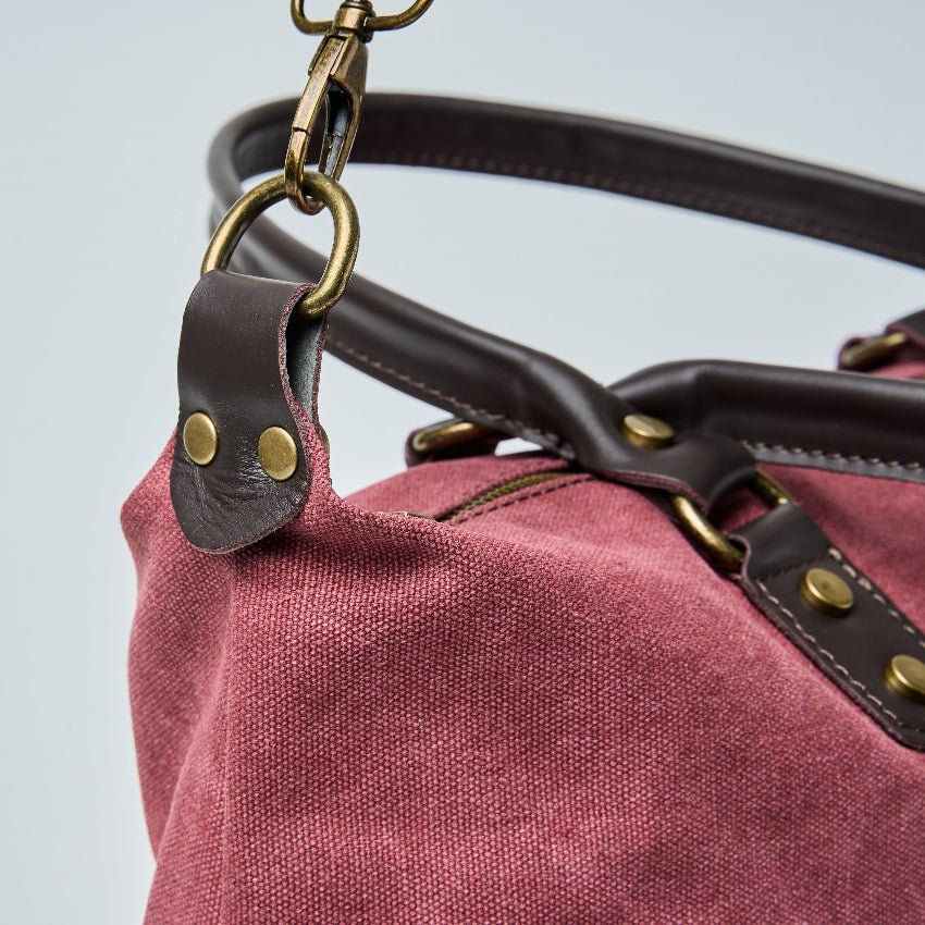 Burgundy tote bag with black straps on a light gray background