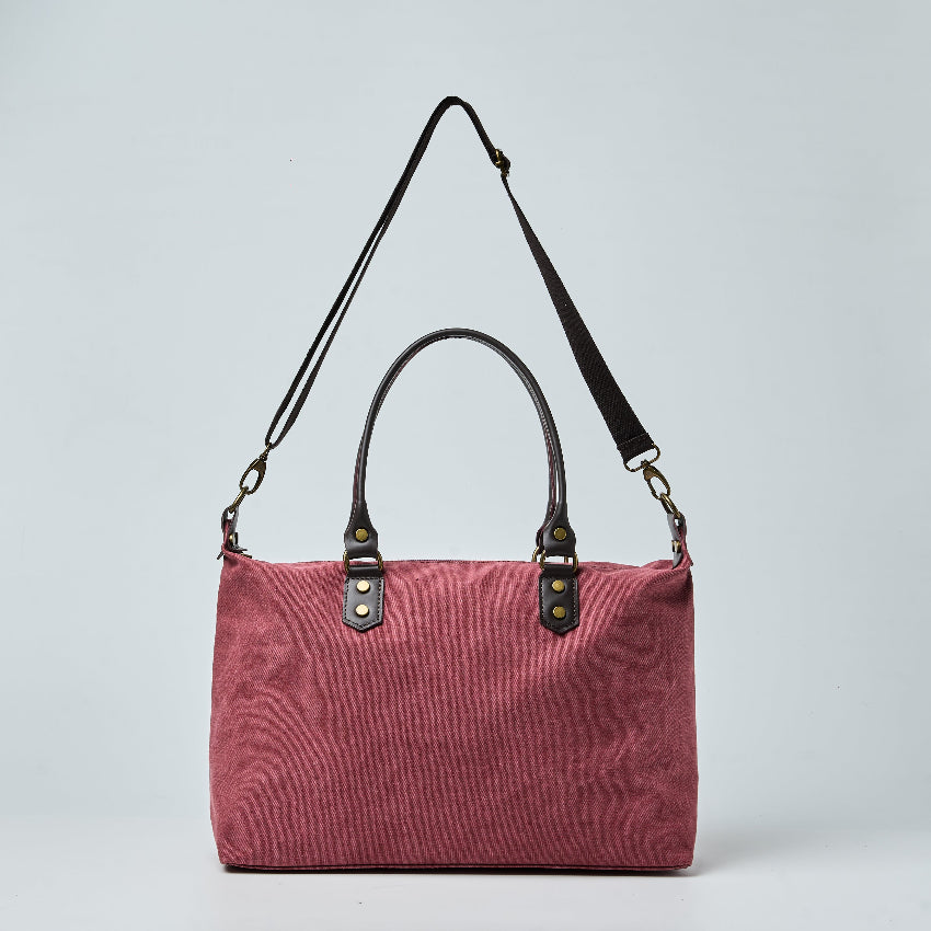 Burgundy tote bag with black straps on a light gray background