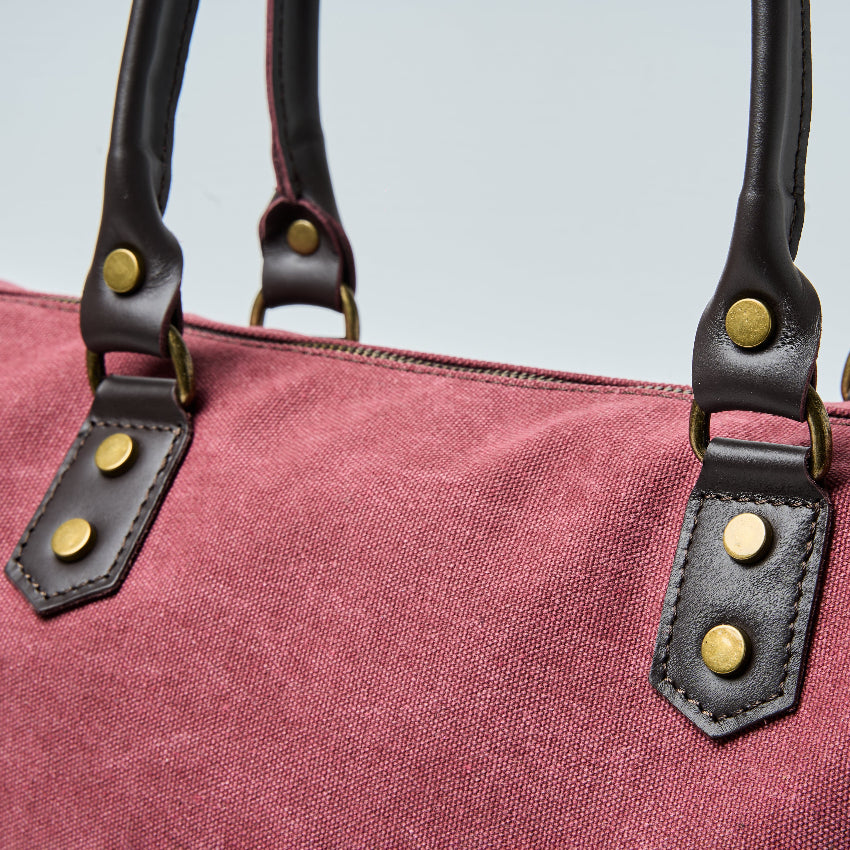 Burgundy tote bag with black straps on a light gray background