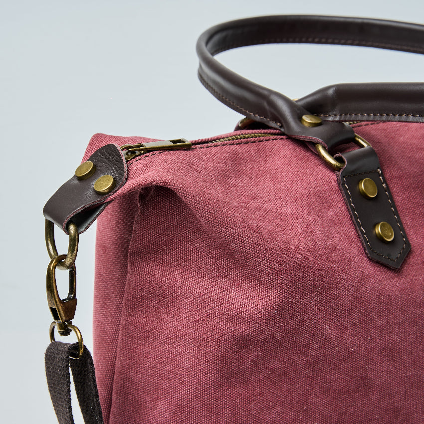 Burgundy tote bag with black straps on a light gray background